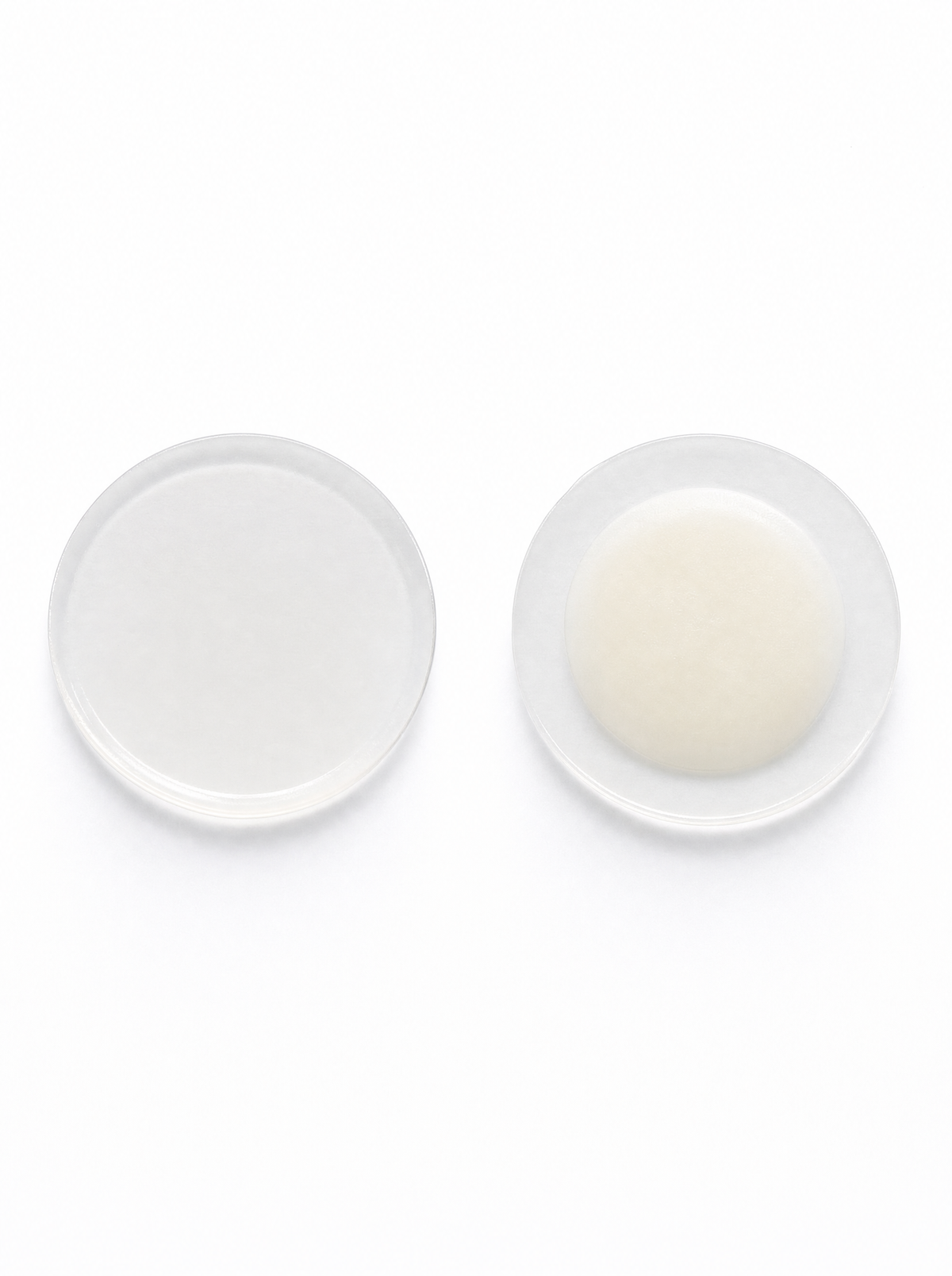 A fresh clear Caluna hydrocolloid dot beside a used white dot, showing when a pimple patch is done and ready to change