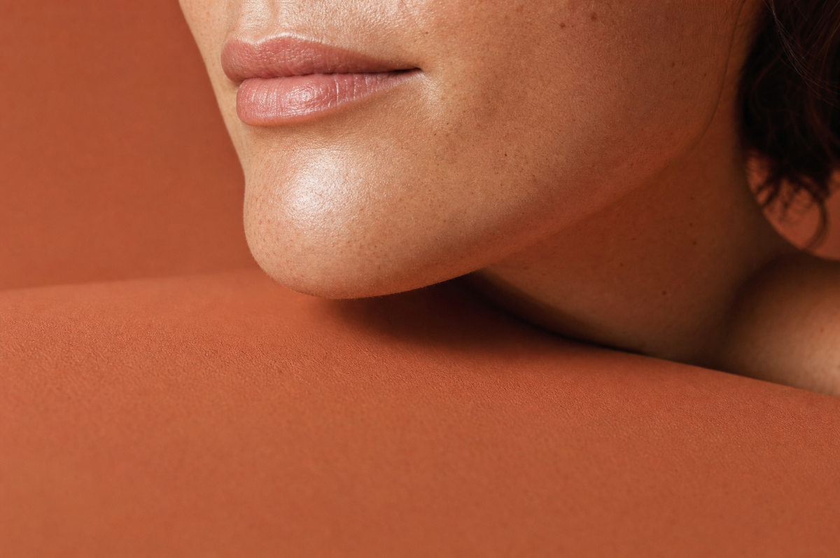 Terracotta editorial close-up of an adult woman lower face, chin and jawline with calm natural skin