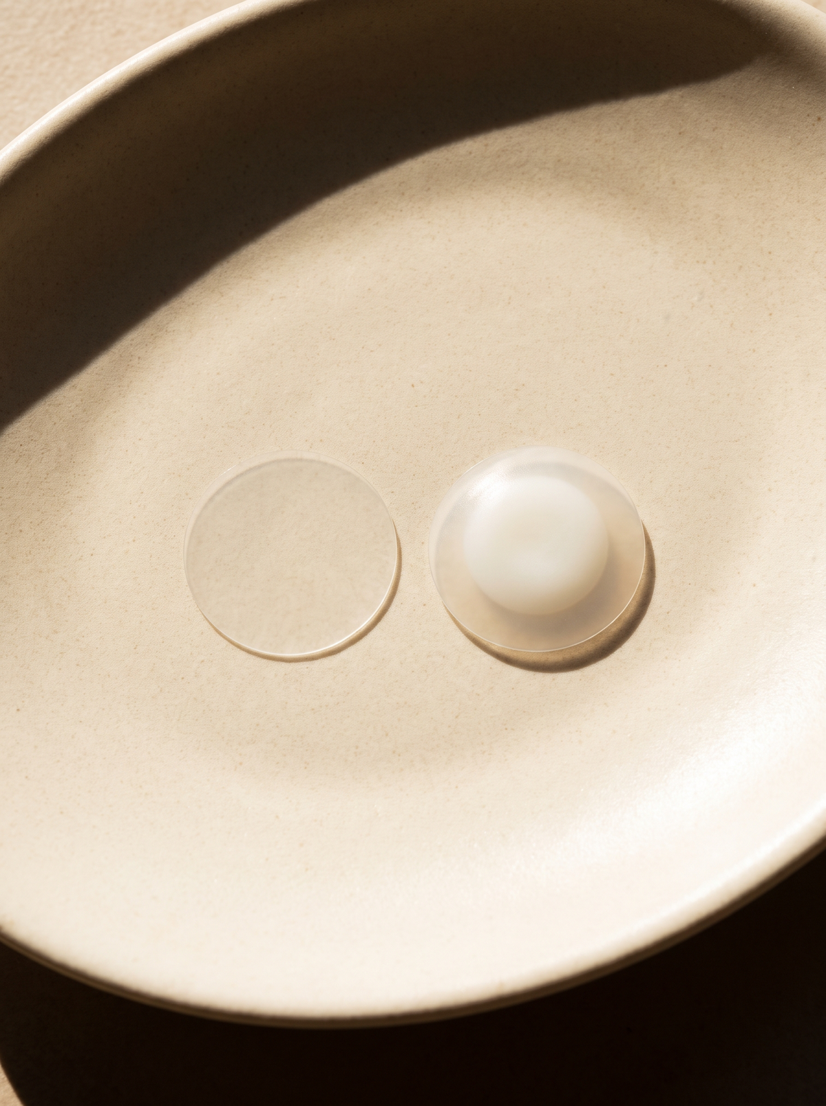 Two small hydrocolloid dots on cream ceramic, one clear and one turned white